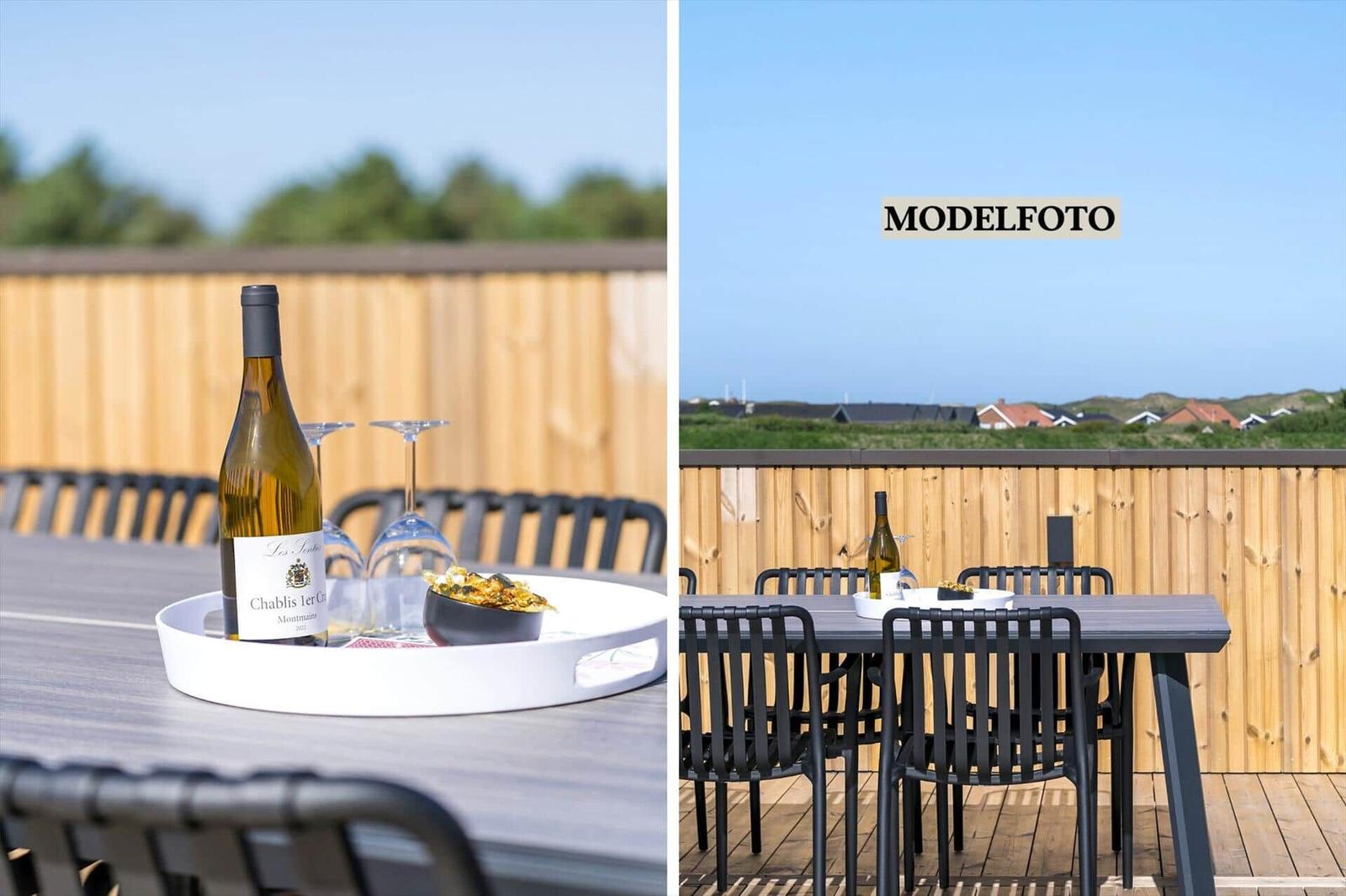 Terrasse mit Tisch, Stühlen und Wein. Blick auf grüne Landschaft.