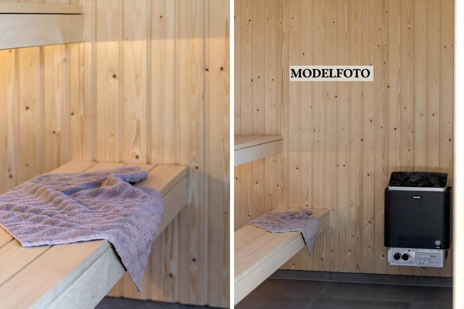 Sauna mit Holzwand, Sitzbank und Heizgerät. Handtuch liegt auf der Bank.