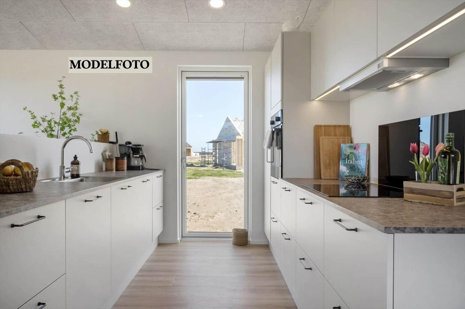 Moderne Küche mit weißen Schränken und Blick auf Außenbereich.