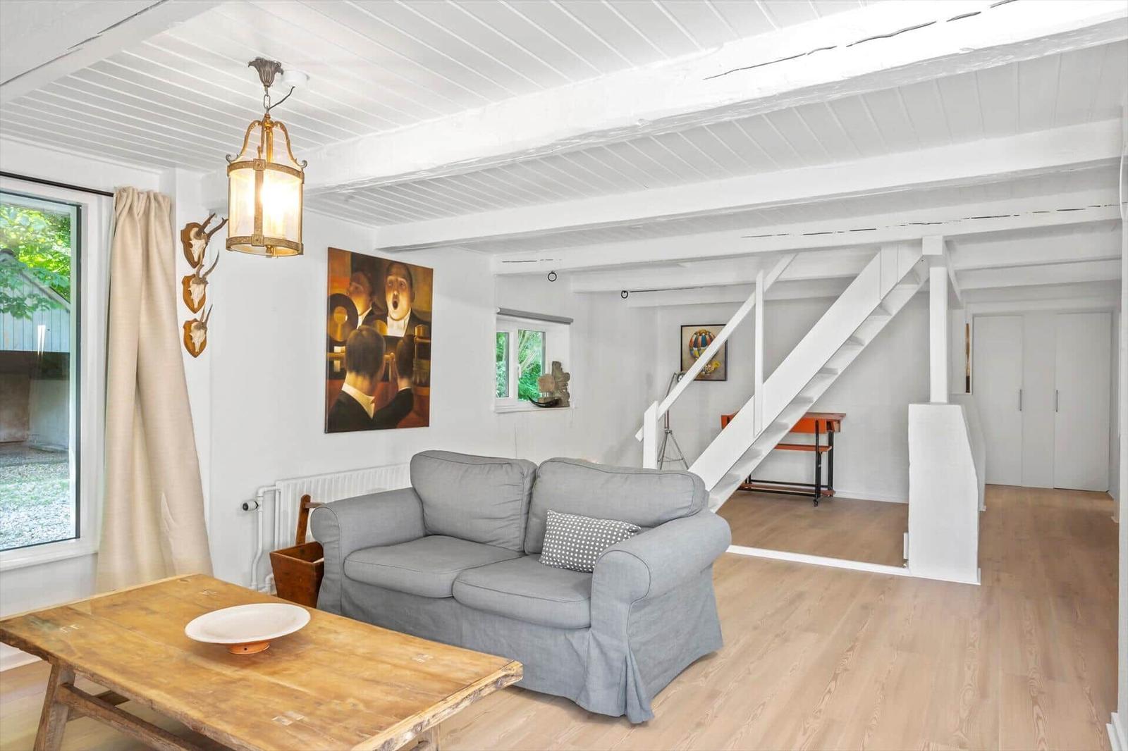 Wohnzimmer mit Sofa, Holztisch und Treppe zur oberen Etage.