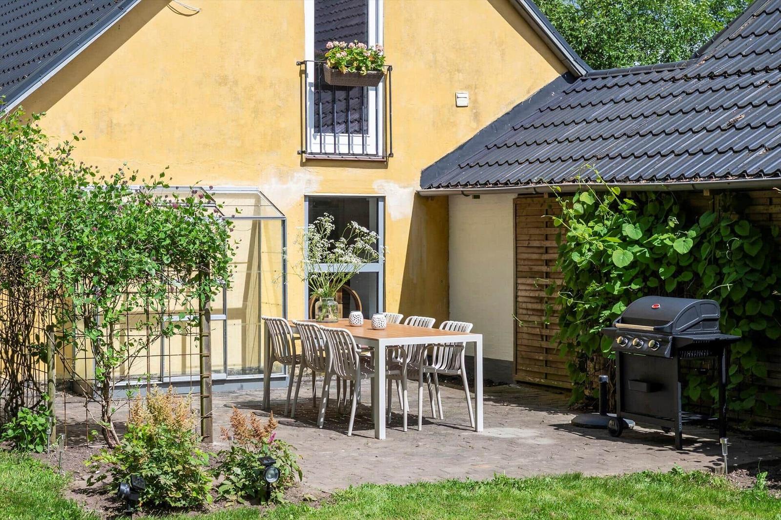 Hinterhof mit Tisch, Stühlen, Grill und Blumenkasten an der Wand.