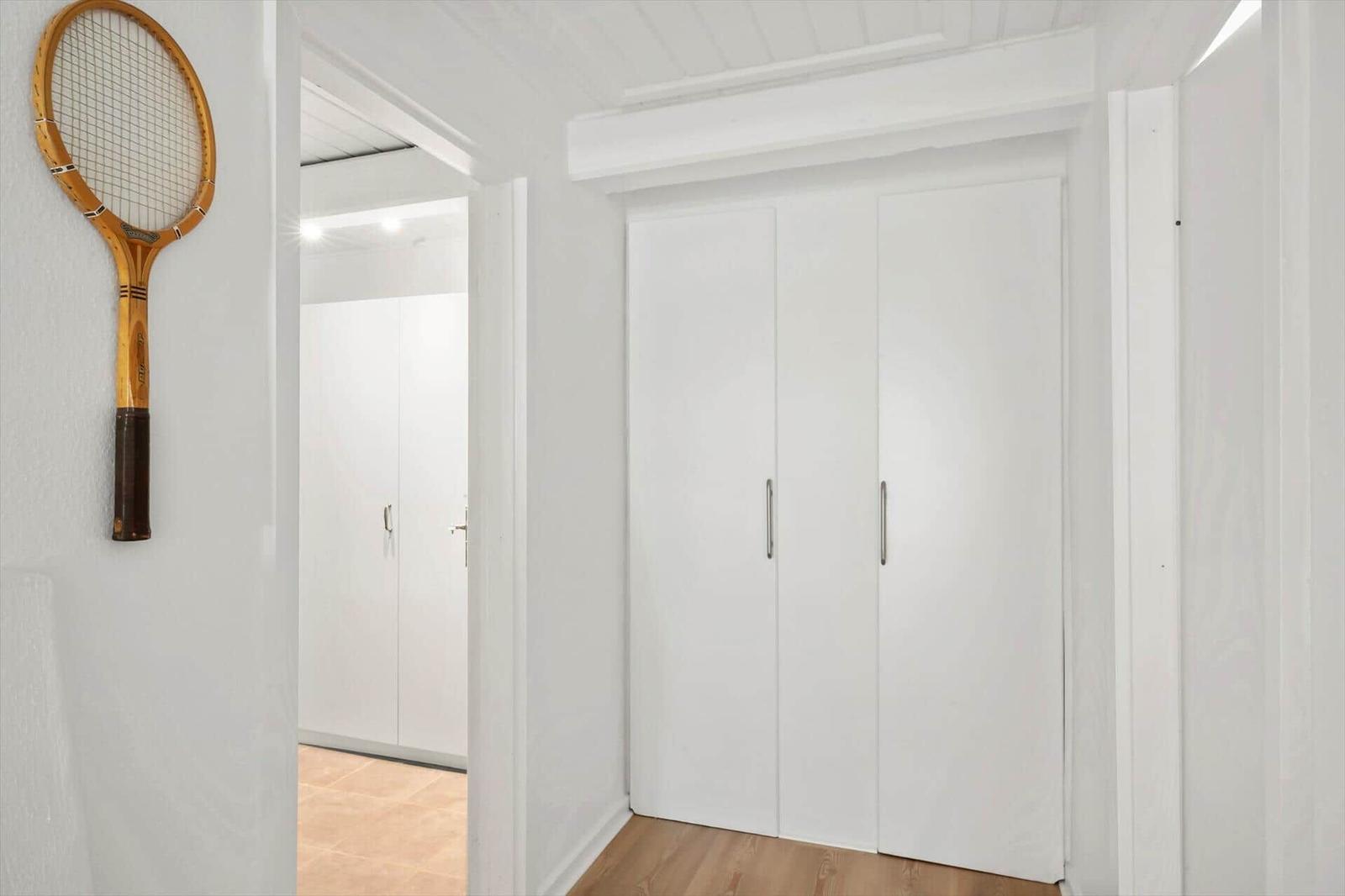 Flur mit weißen Schränken und Tennis racket an der Wand