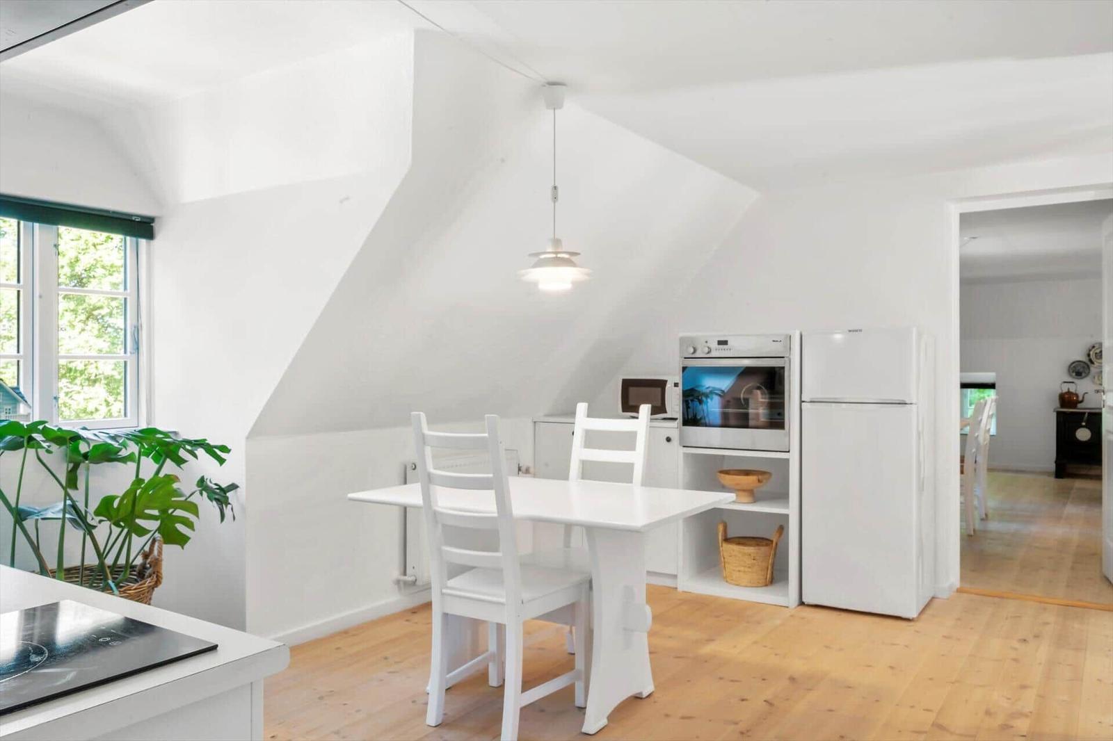 Küche mit Esstisch, Kühlschrank und Ofen unter Dachschrägen.