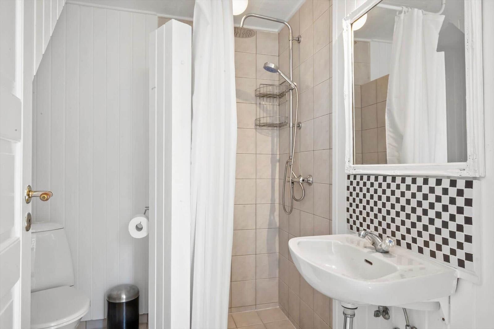Badezimmer mit Dusche, Waschbecken und Toilette.