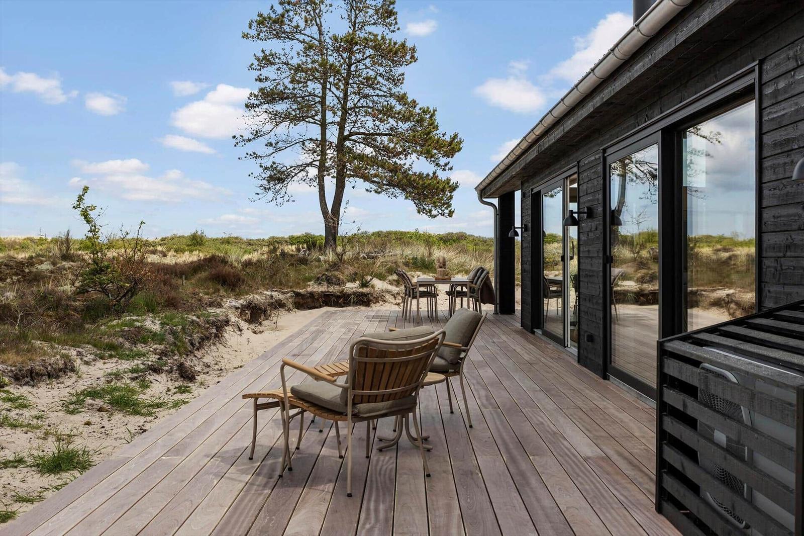 Terrasse mit Sitzgelegenheiten und Blick auf Dünenlandschaft.