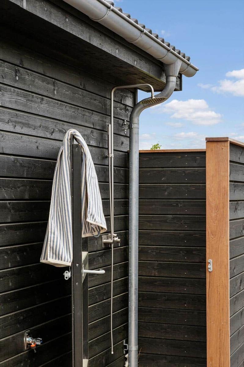 Außen-Dusche an der Wand mit Handbrause und Handtuchhalter.