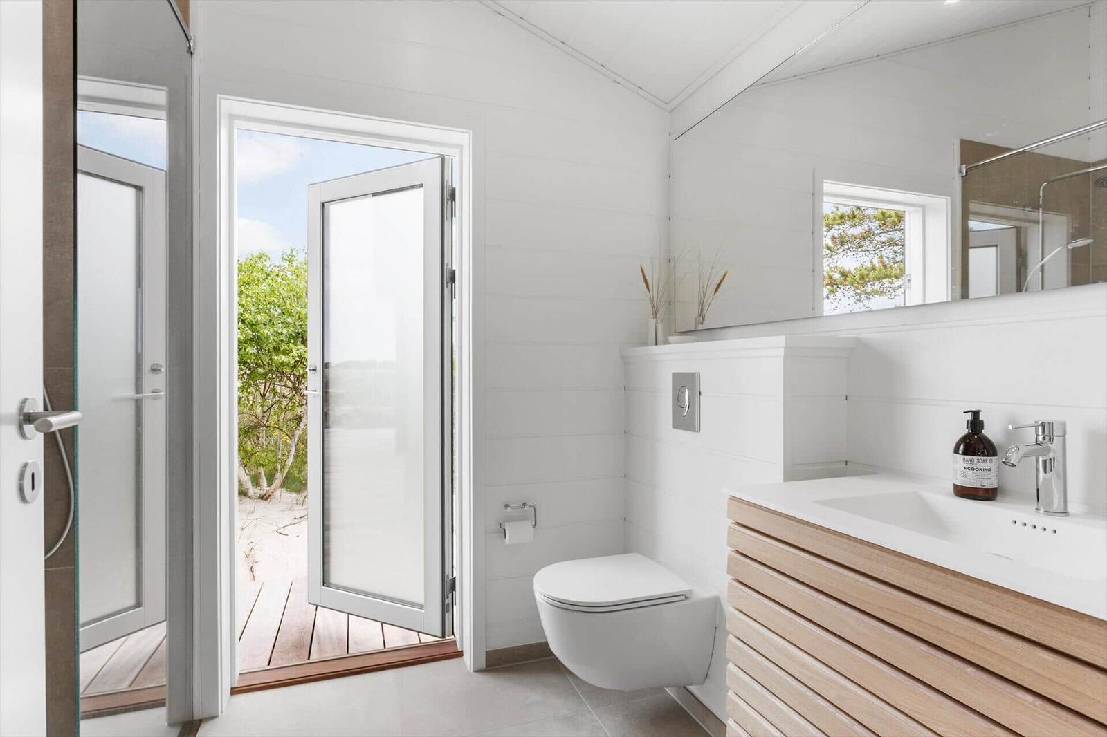 Badezimmer mit Toilette, Waschbecken und Tür zum Außenbereich.