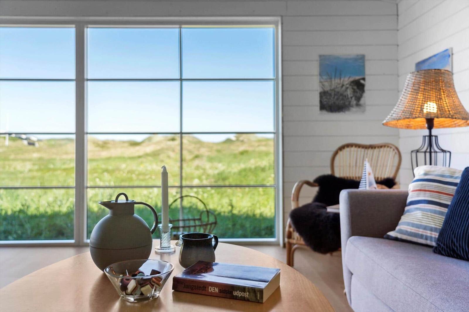 Ein Wohnzimmer mit großem Fenster, Sitzgelegenheiten und Tisch mit Geschirr.