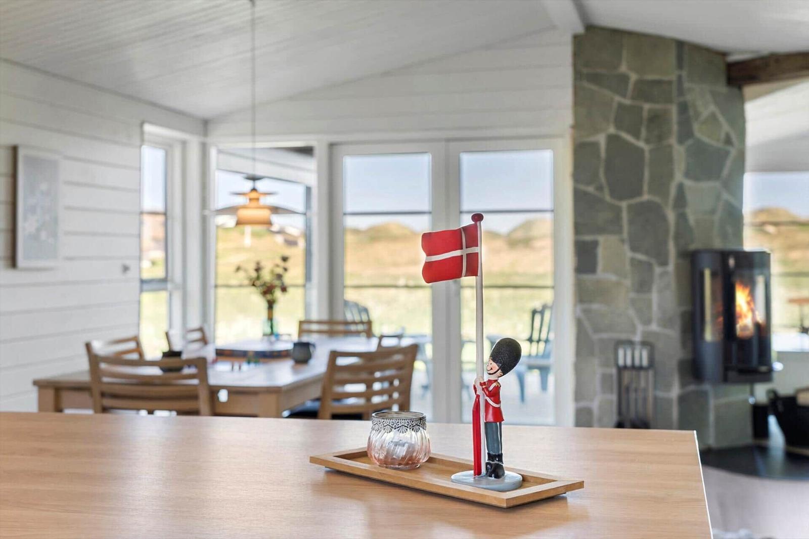Tisch mit dänischer Flagge und Kerze im Esszimmer mit Steinofen und Blick auf die Landschaft.