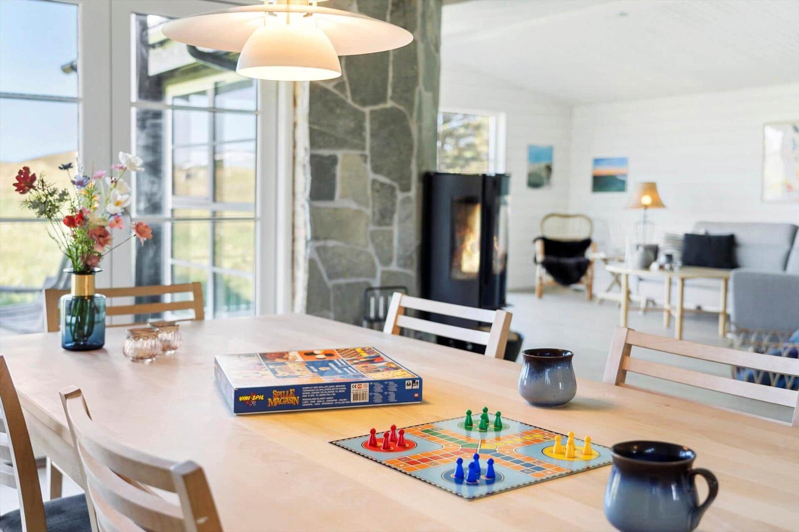 Esstisch mit Brettspiel und Blumen vor Steinwand und Kamin