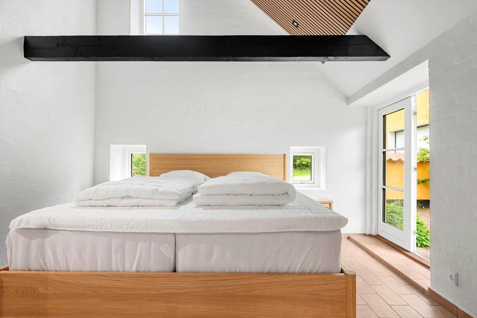 Bedroom with bed, windows, and door to an outdoor area.