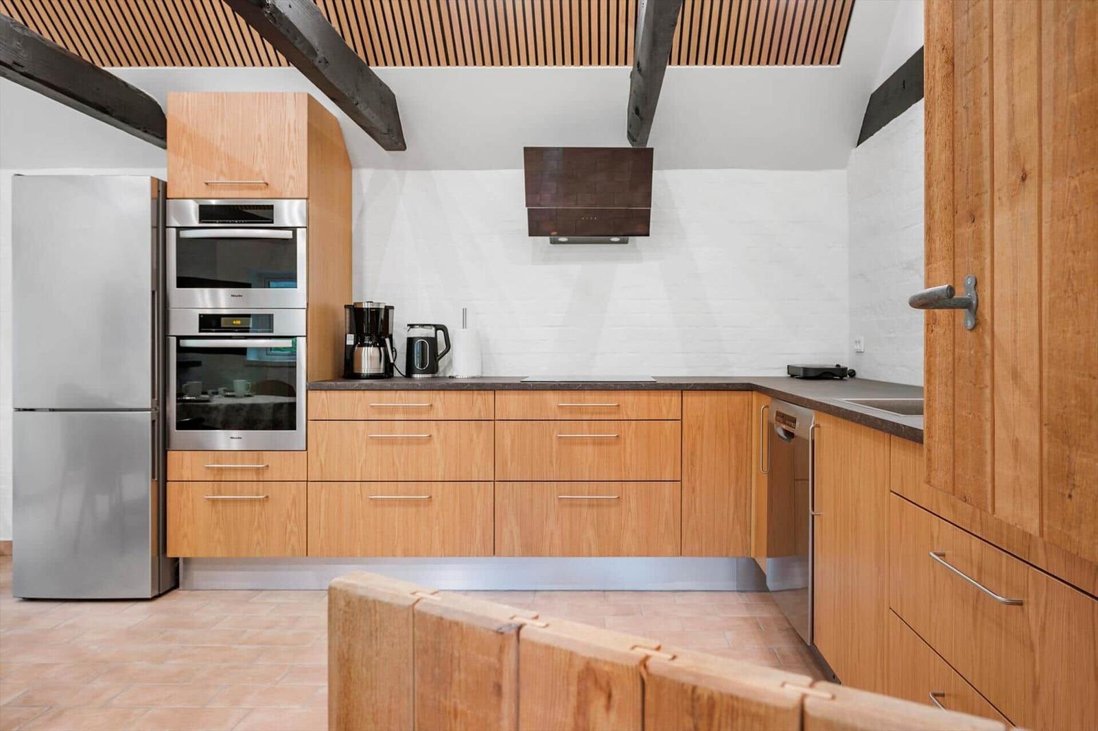 Kitchen with wooden cabinets, stainless steel appliances, and white wall.