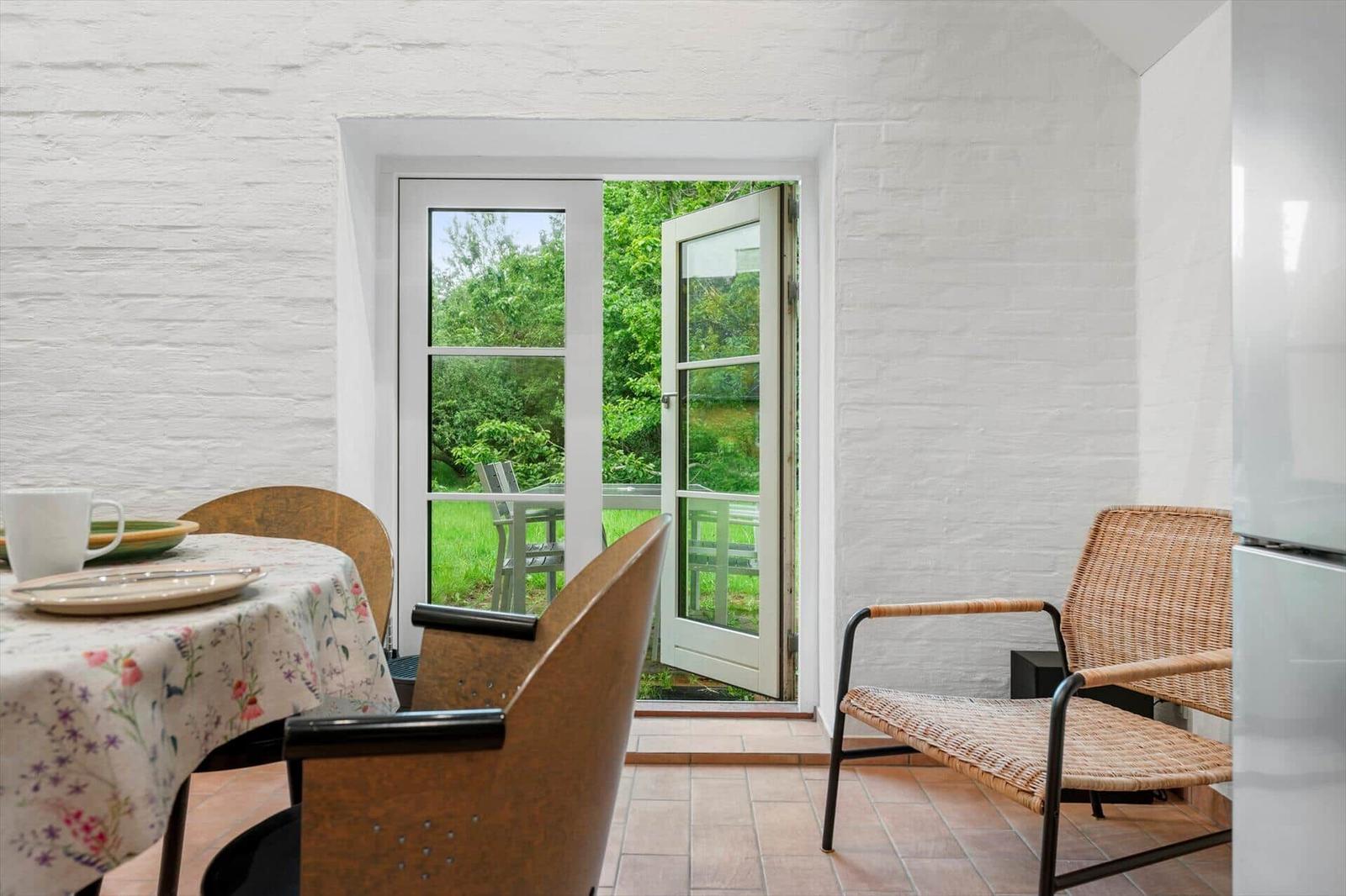 Dining area with table, chairs, and open door to the garden.
