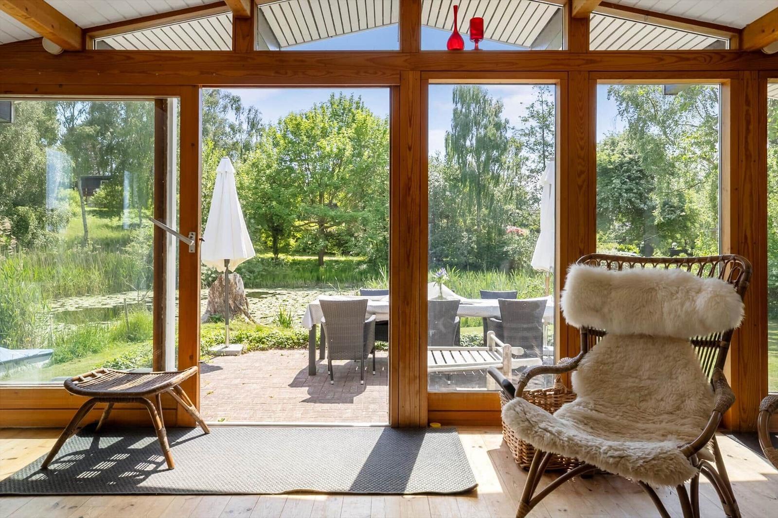 Seating area with chair and fur, view of garden with table and parasol.