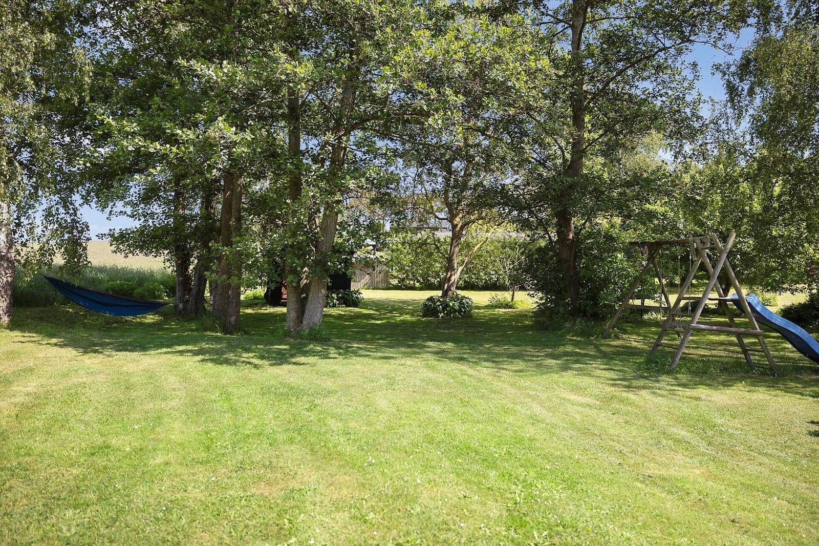 Large green garden with swing and slide under trees.