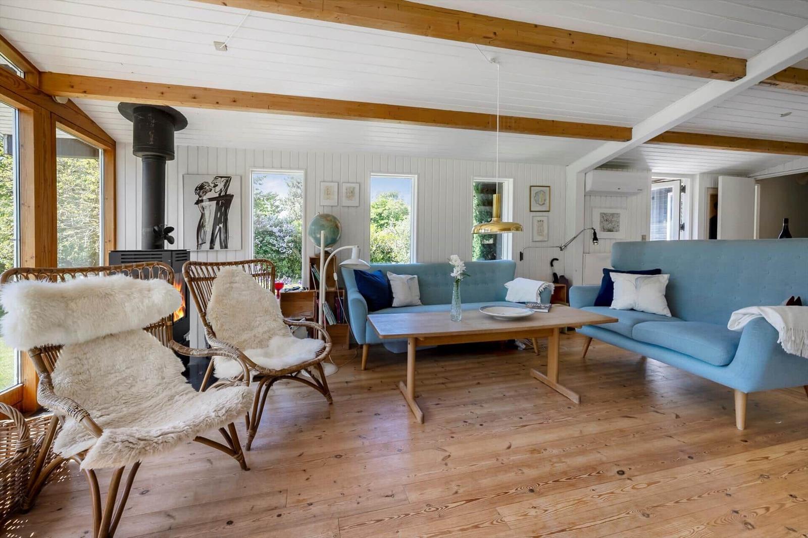 A living room with wooden floor, blue sofas, and a fireplace.