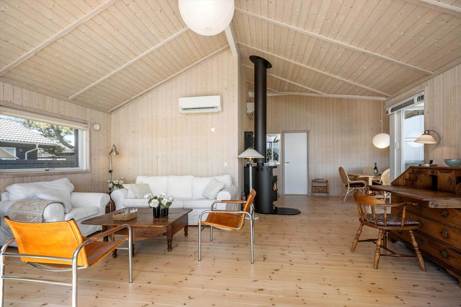 Wohnzimmer mit Holzdecke, Sofa, Stühlen und Kamin