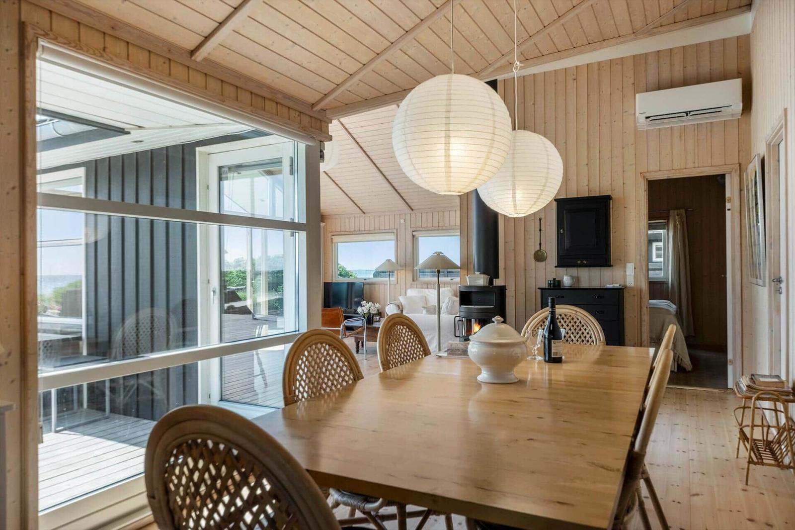 Esszimmer mit Holztisch, Stühlen und Blick auf Terrasse. Holzwände und Decke.