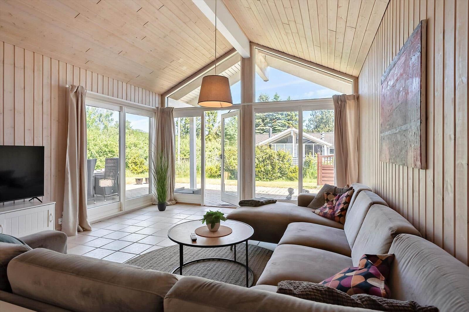Wohnzimmer mit Sofa, Couchtisch und großen Fenstern zur Terrasse.