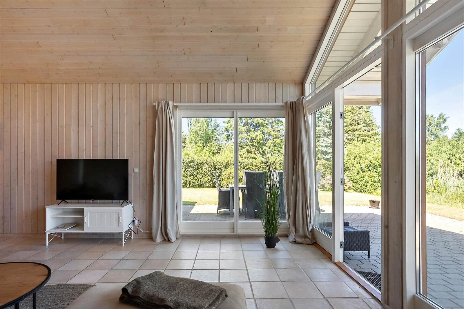 Wohnzimmer mit TV, Terrasse und Blick auf den Garten.