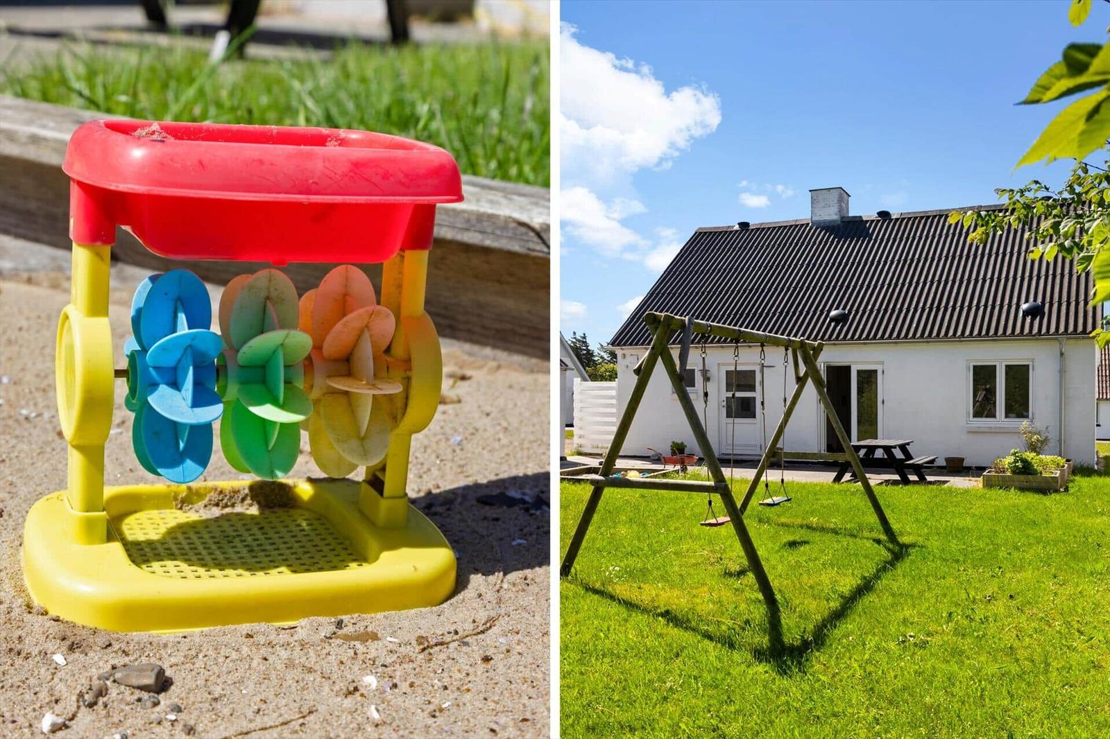 Kinder-Spielzeug auf Sand und Haus mit Schaukel im Garten.