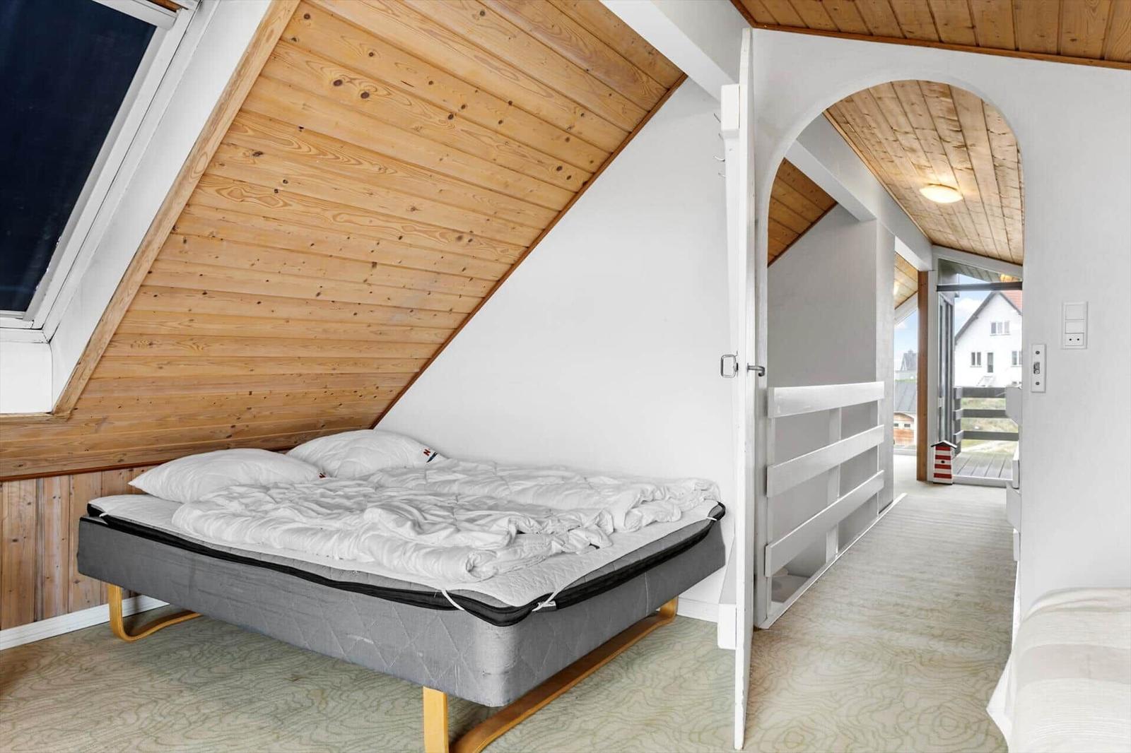 Schlafzimmer mit Dachschrägen, Bett und Blick in Flur