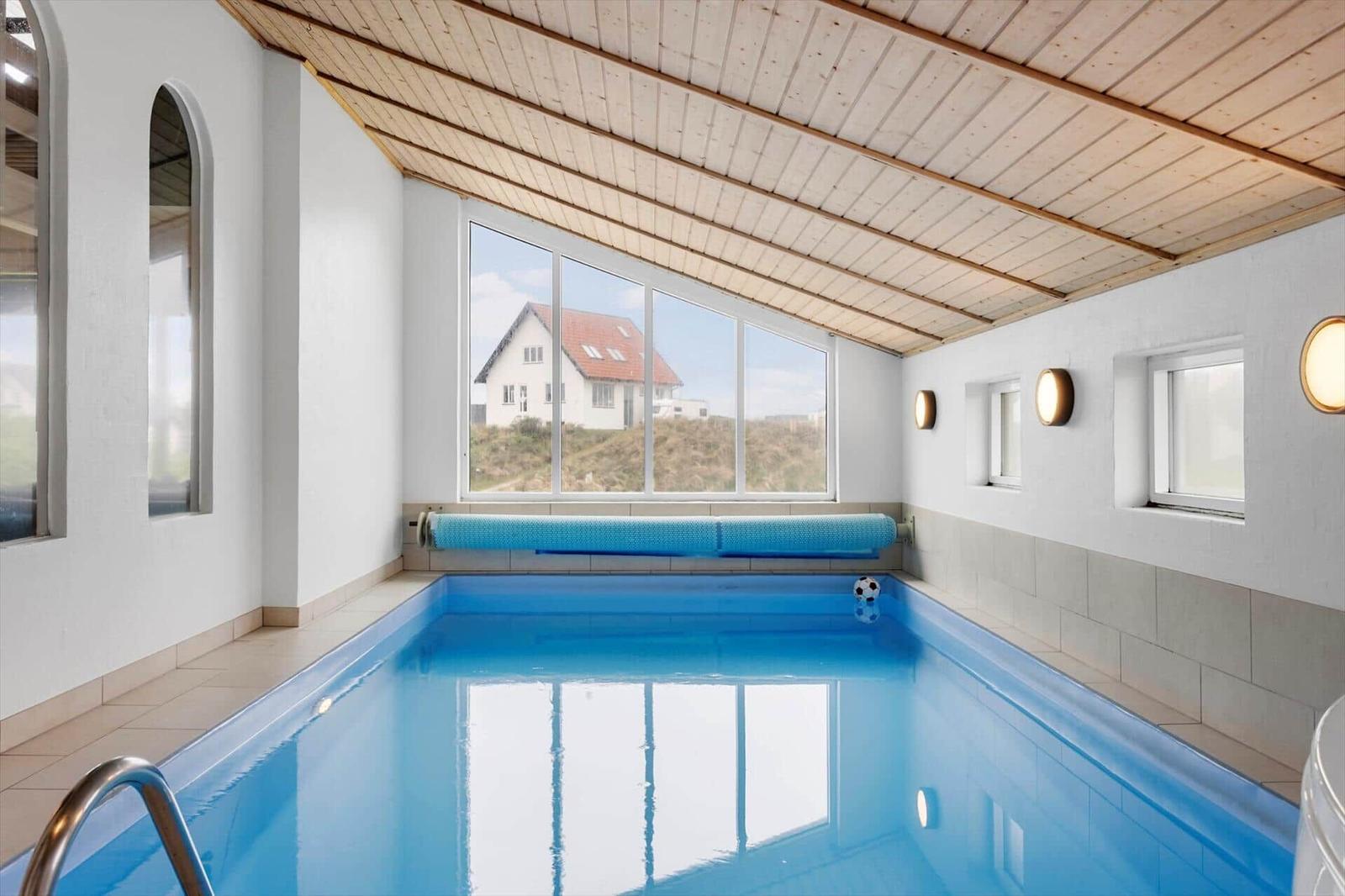 Innenpool mit großem Fenster und Holzdecke. Fußball im Wasser.