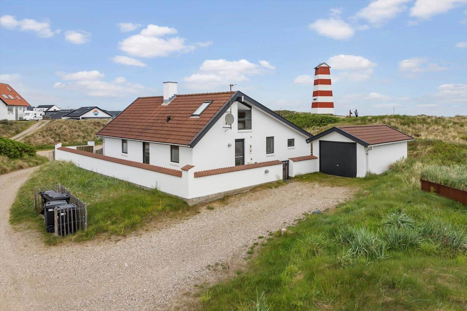 Moderne Villa mit Garage und Leuchtturm im Hintergrund