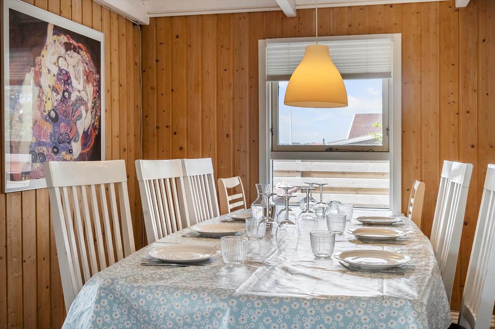 Esszimmer mit Holzwand, gedecktem Tisch und Fensterblick.