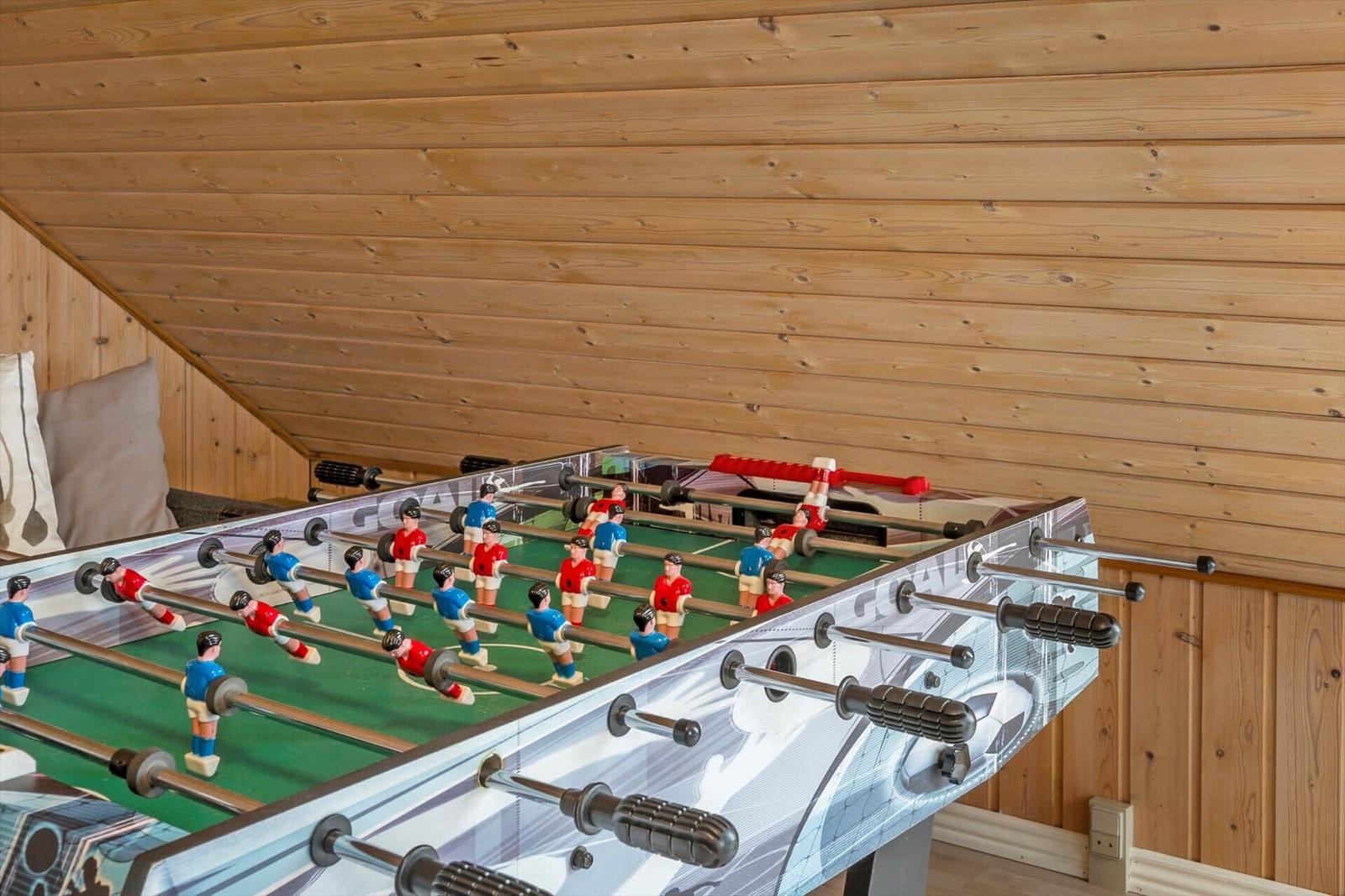 Fußballtisch in einem Holzhaus mit geneigtem Dach und Sitzgelegenheit.