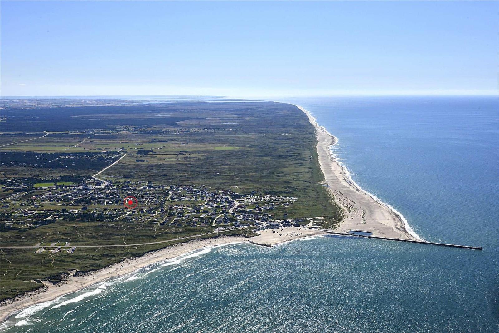 Aerielansicht einer Küstenlandschaft mit Strand, Meer und Siedlung.