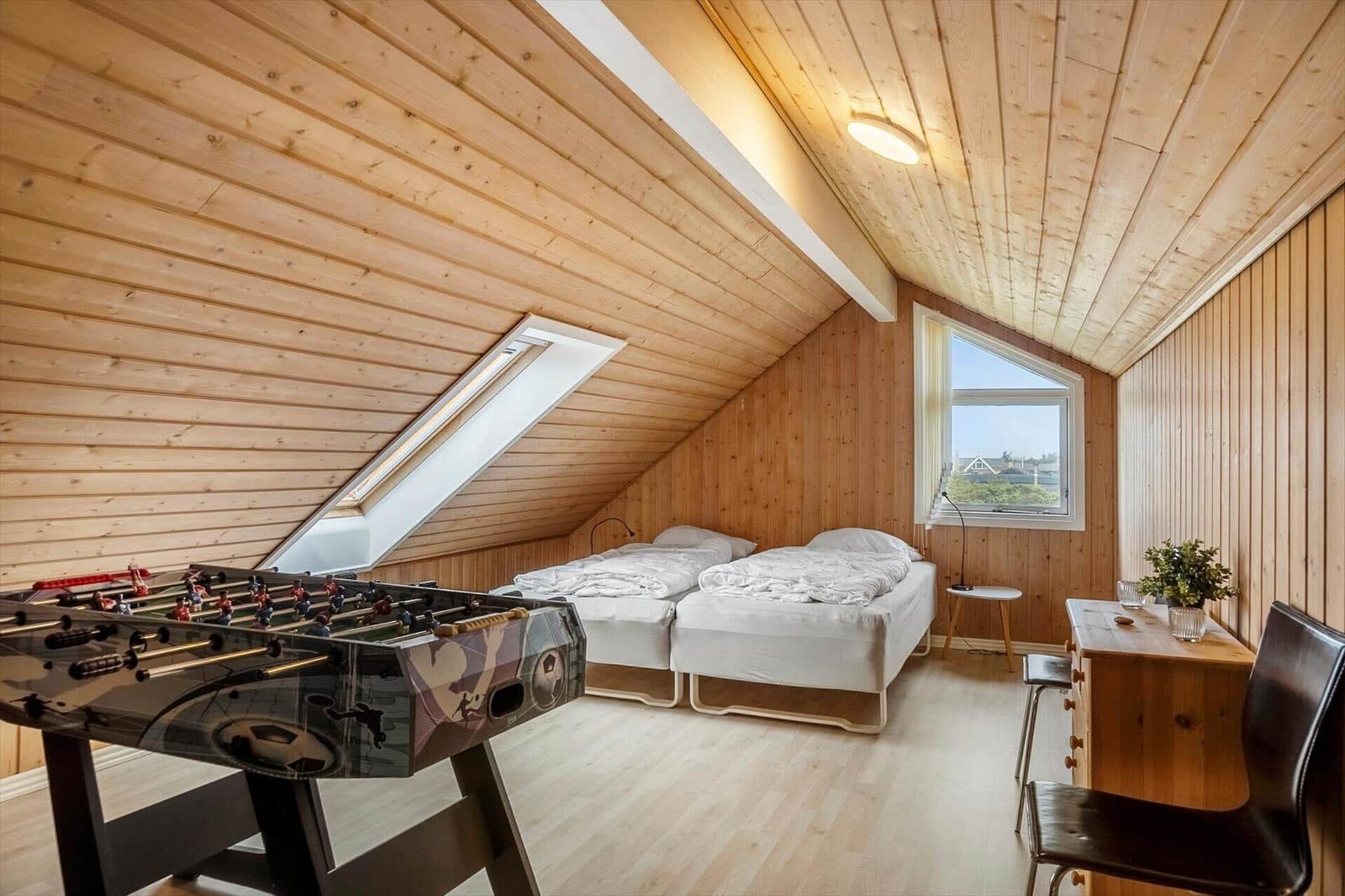 Zimmer mit zwei Betten, Tischfußball und Holzwandverkleidung
