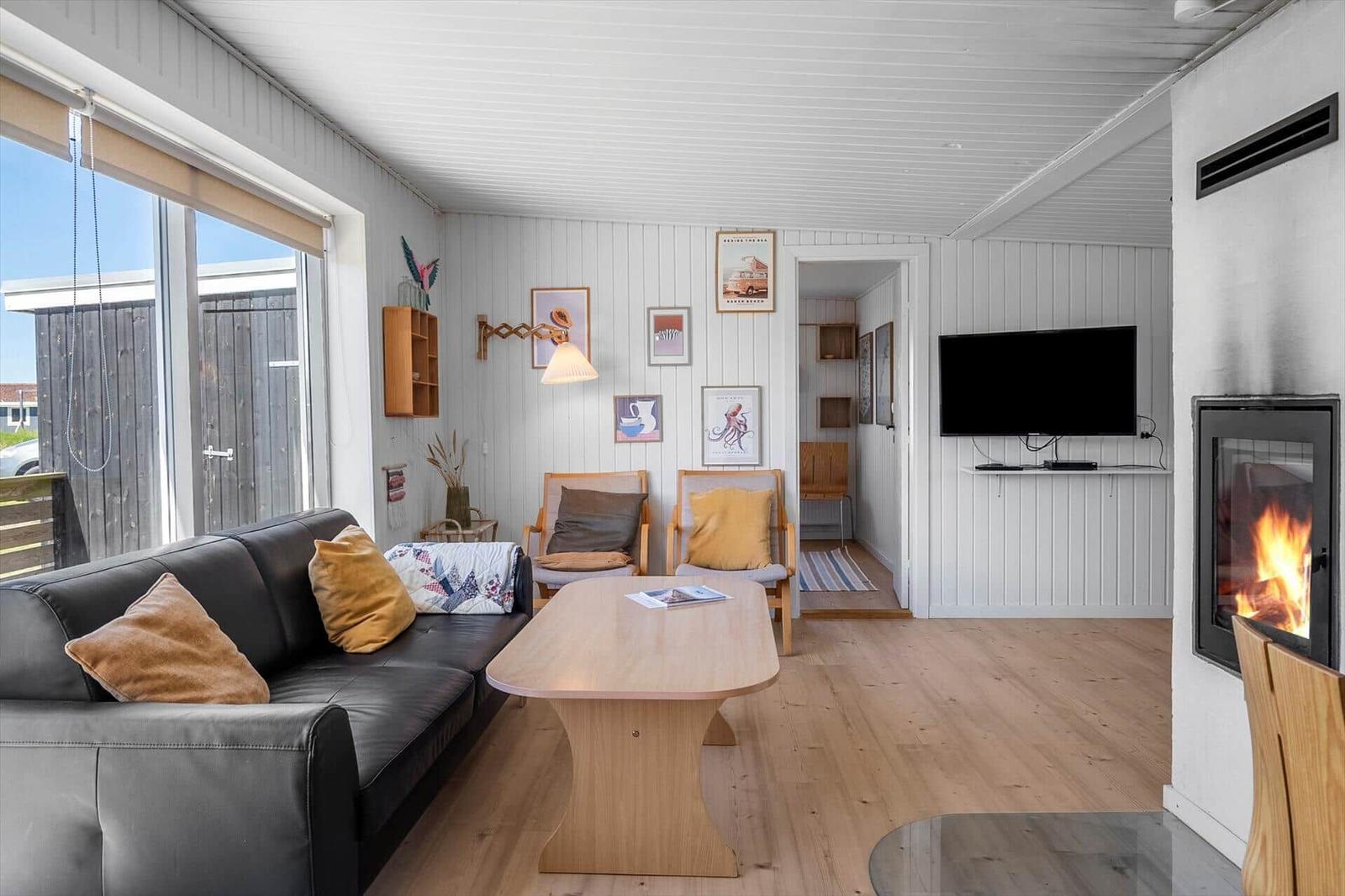 Wohnzimmer mit Sofa, Tisch, Kamin und Fernseher an der Wand.