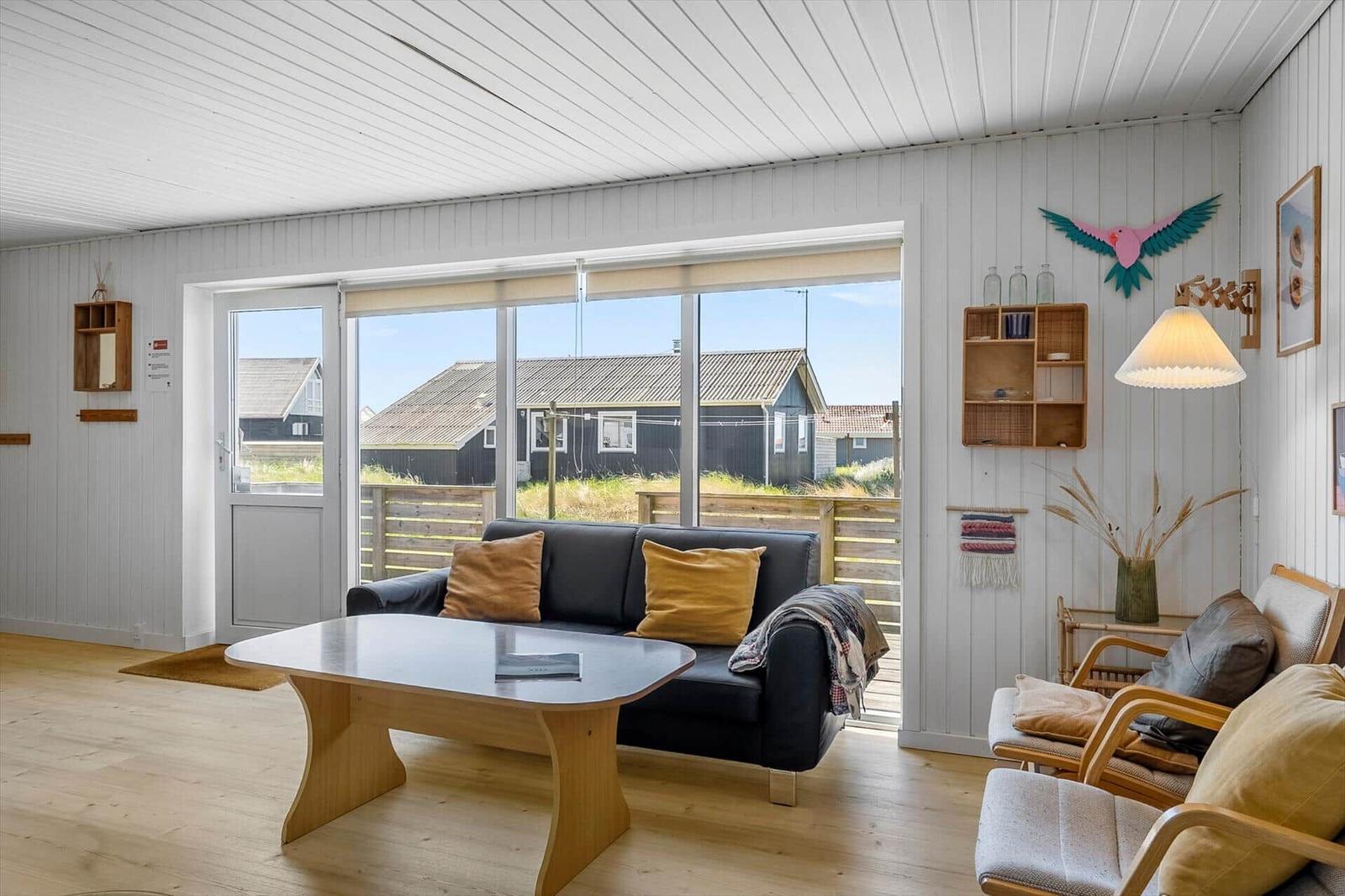 Wohnzimmer mit Sofa, Tisch und Blick auf die Außenterrasse.