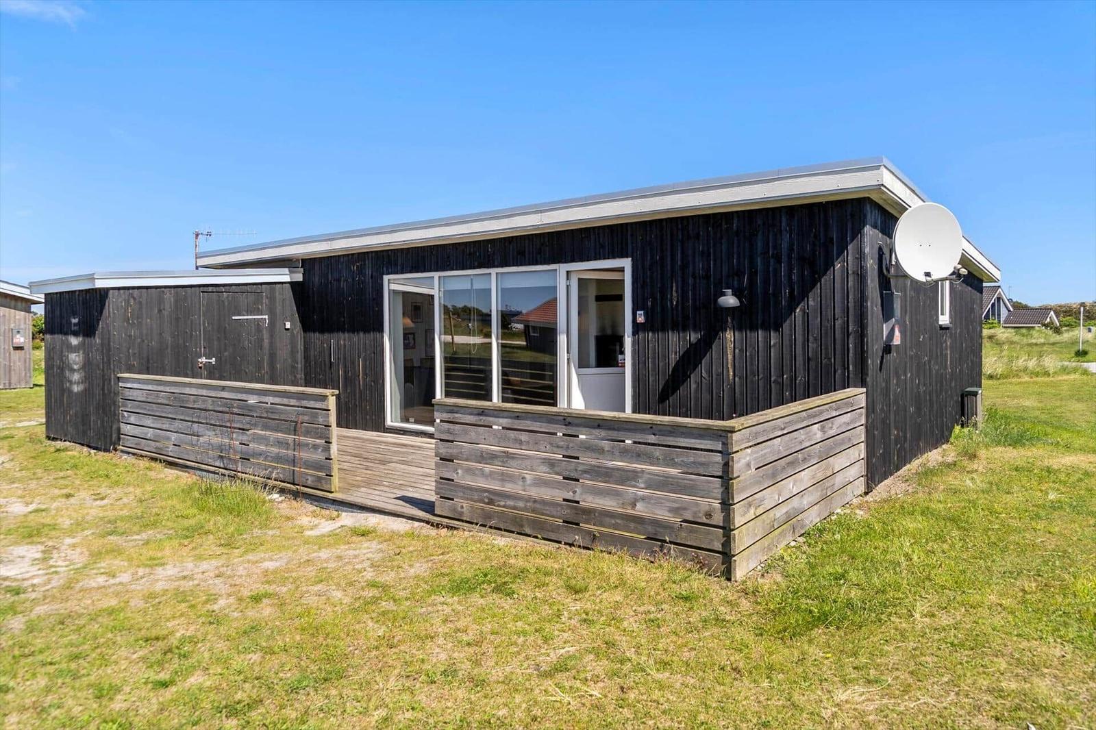 Moderne Holzhütte mit Terrasse und Satellitenschüssel im Freien.