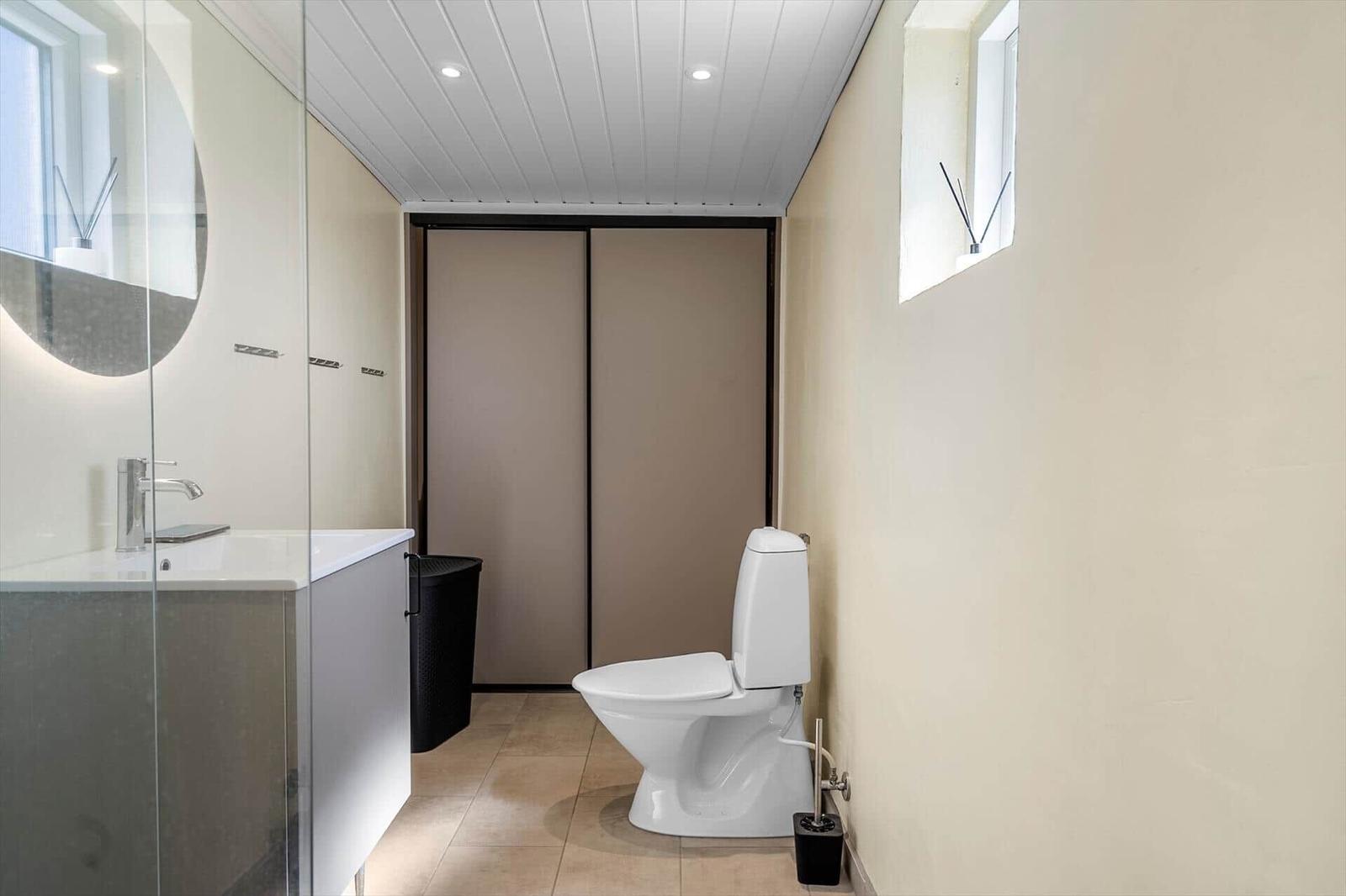 Badezimmer mit Toilette, Waschbecken und Duschbereich mit Glaswand.