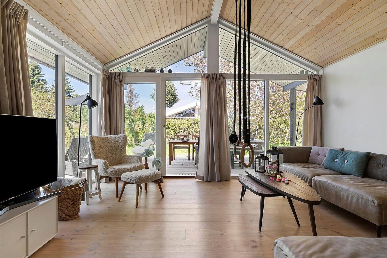 Living room with wooden floor, sofa, armchair, and large window view of garden