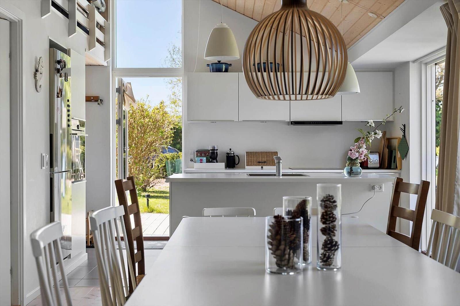 Modern kitchen with dining area, large windows, and wooden ceiling.