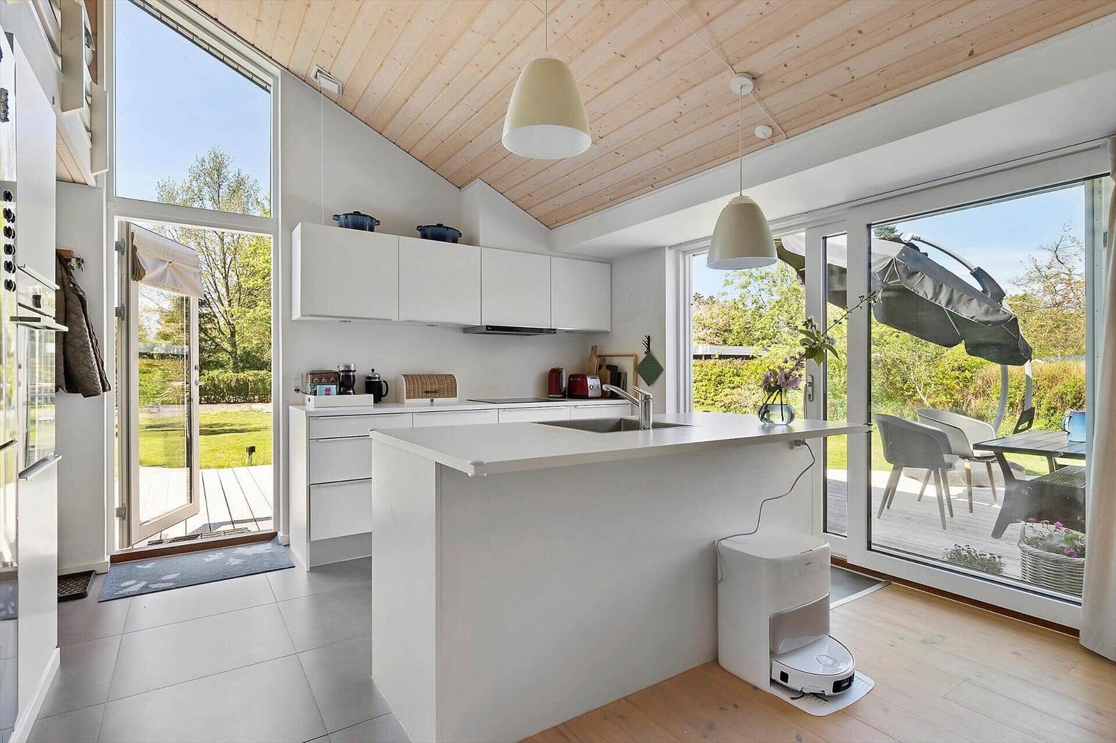 Modern kitchen with white cabinets and island. Large windows to terrace and garden.