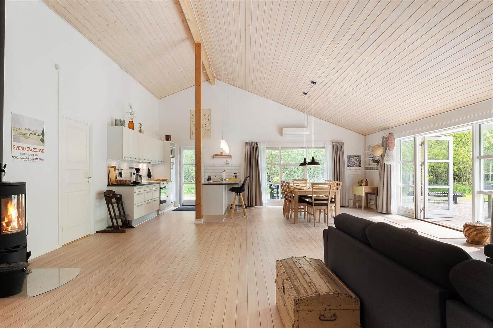 An open space with kitchen, dining area, and living area. Wooden floor and ceiling.