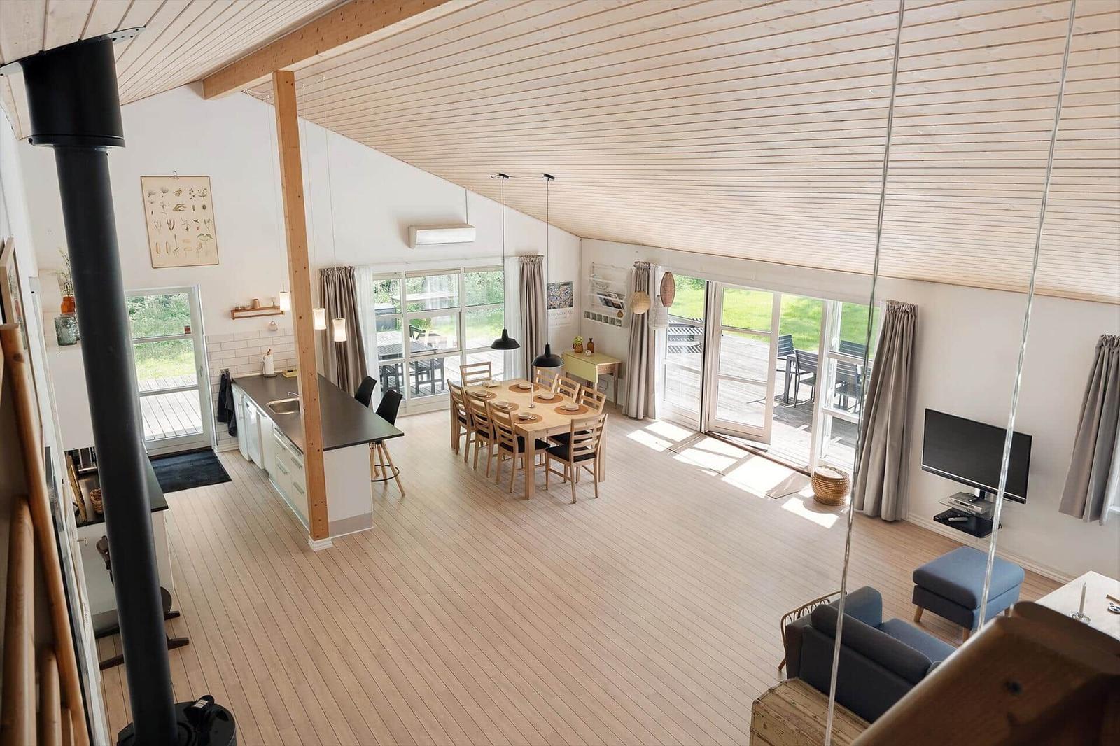 Large open space with kitchen, dining area, and living area. Wooden ceiling and terrace.