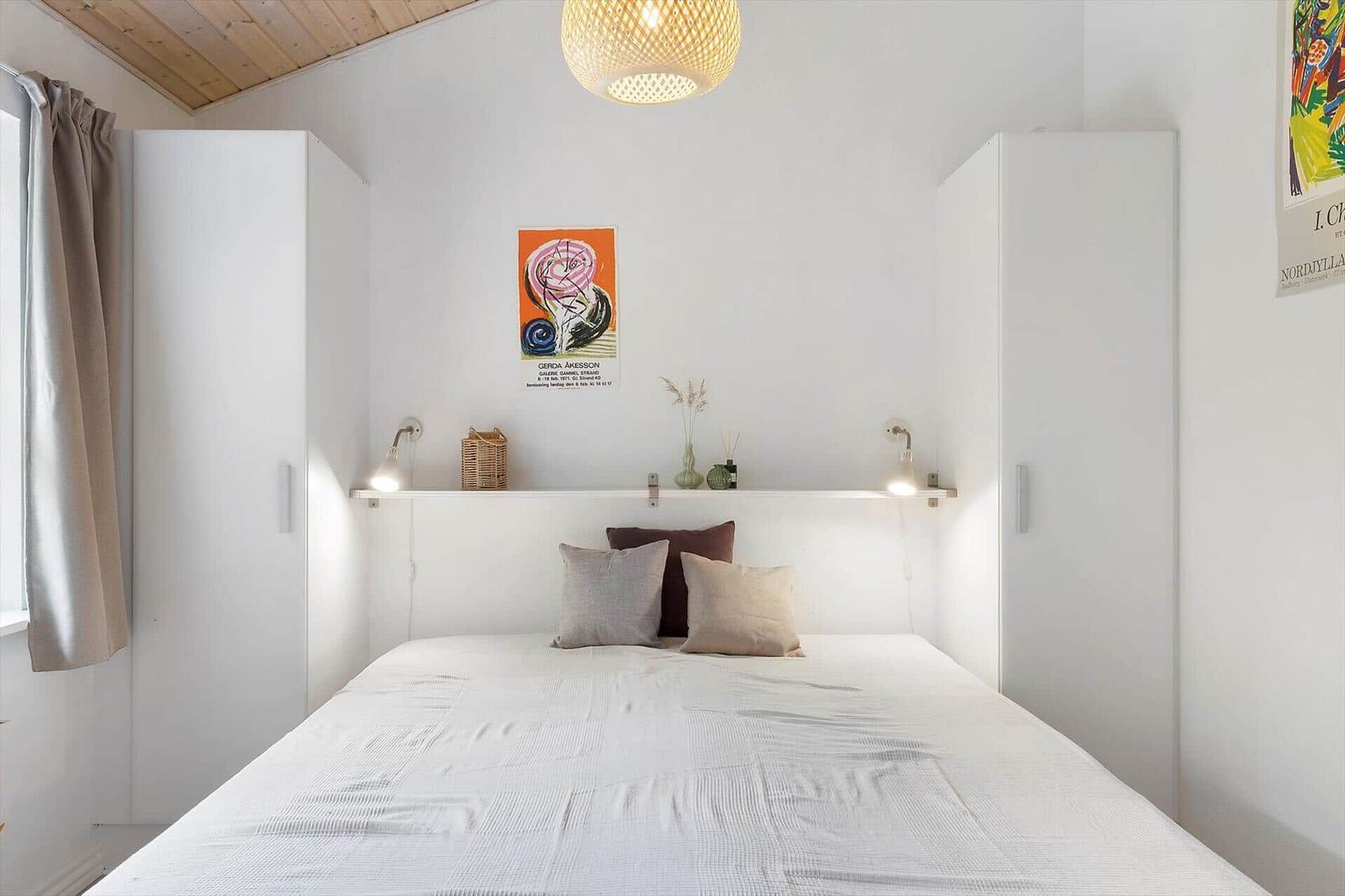 Bedroom with bed, white wardrobes, and wall posters.