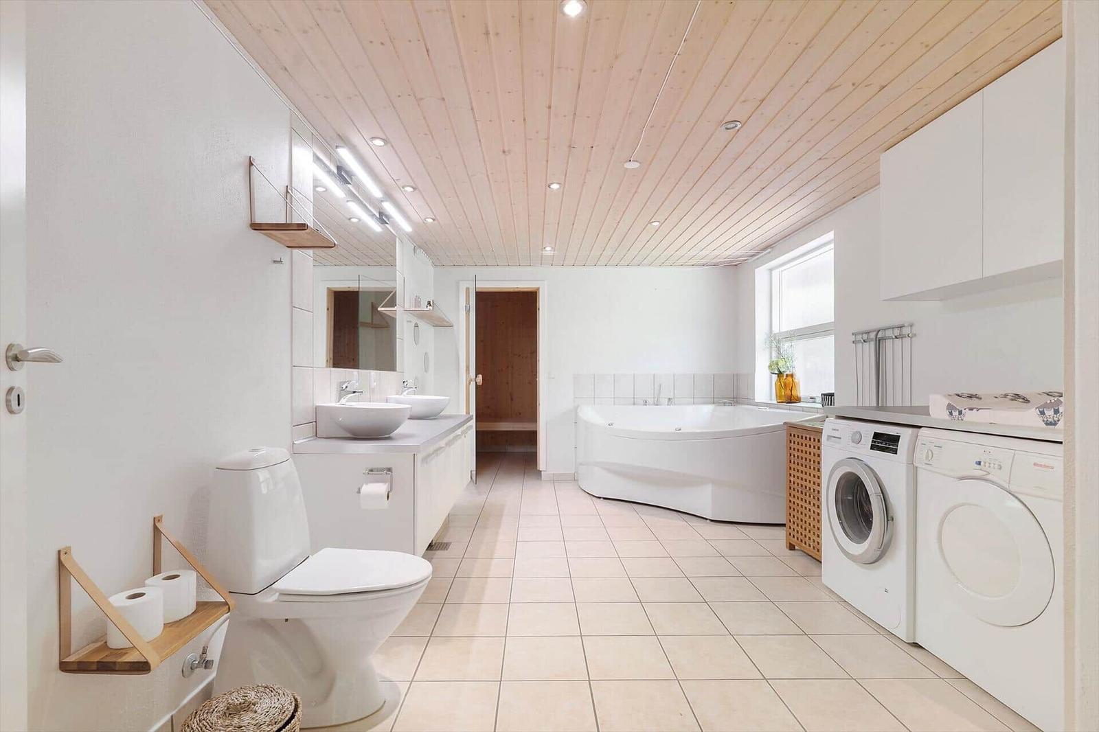 Bathroom with bathtub, washing machine, and dryer.