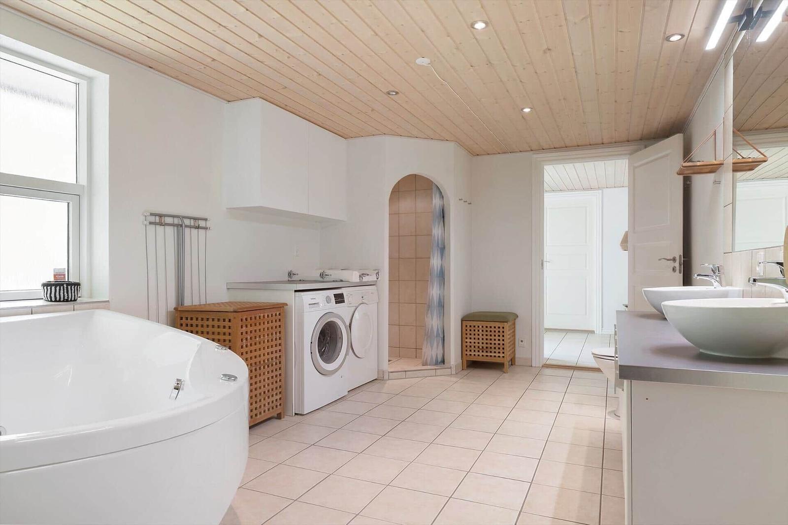 Bathroom with bathtub, washing machine, and shower