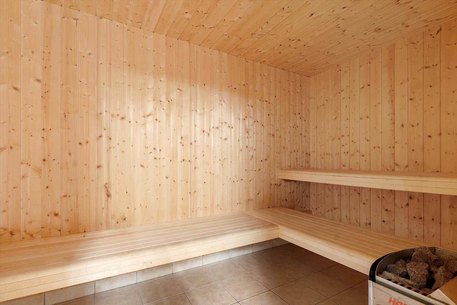 Sauna with wooden walls and benches, tiled floor and wood stove