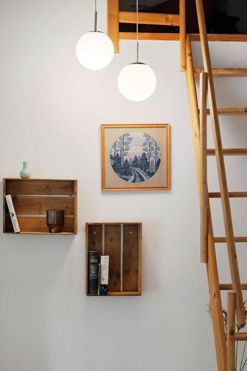 Wall with wooden shelves, picture, and ladder. Two pendant lights hang above.