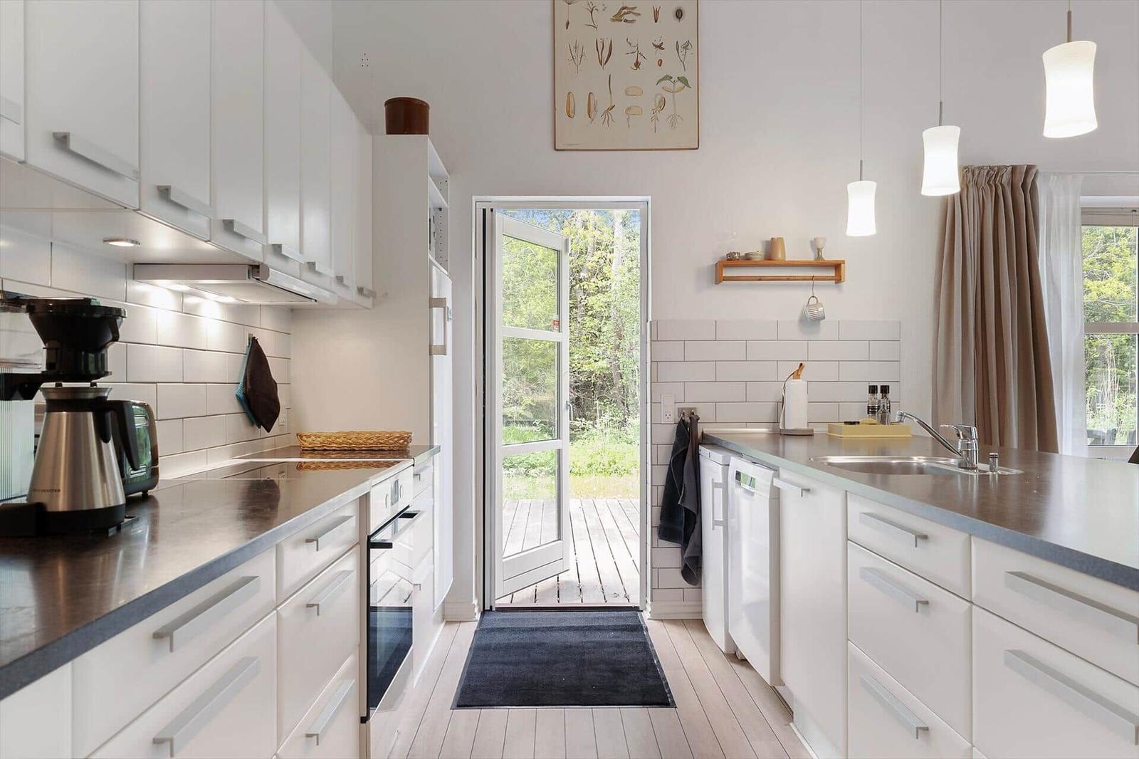 Kitchen with white cabinets, stainless steel countertop, and door to balcony.