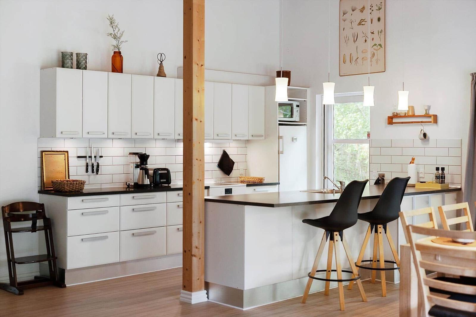 Kitchen with white cabinets, black countertop, and wooden stools at the counter.