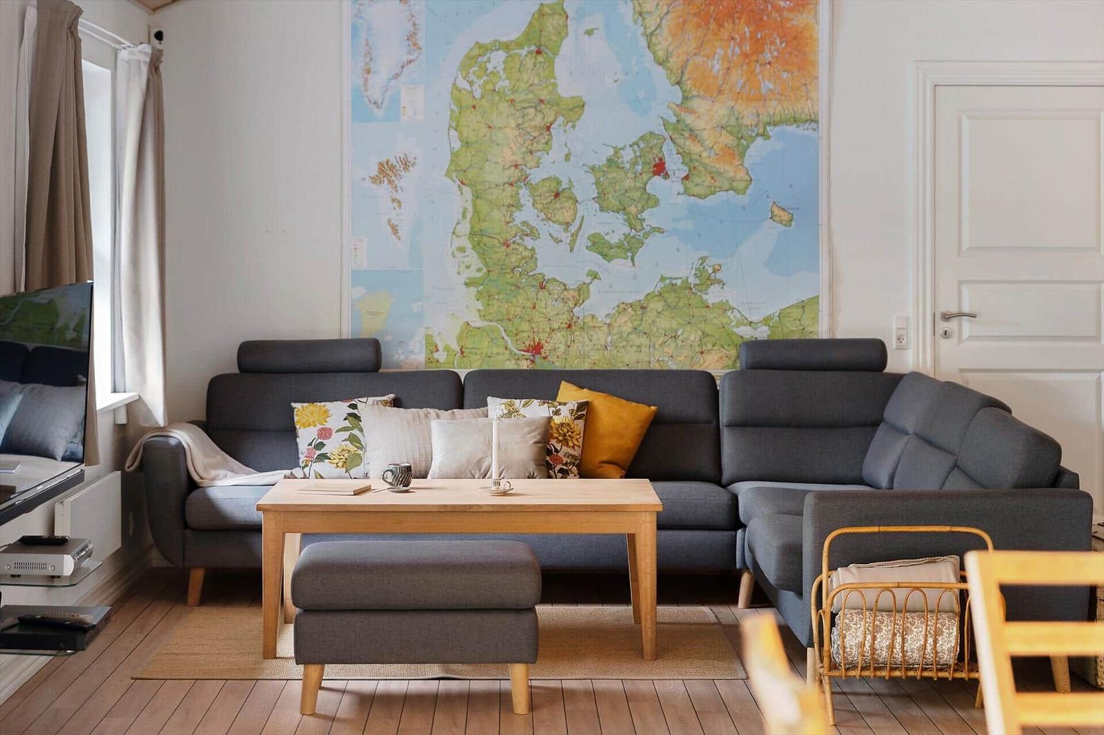 Living room with gray sofa, wooden table, and large wall map.