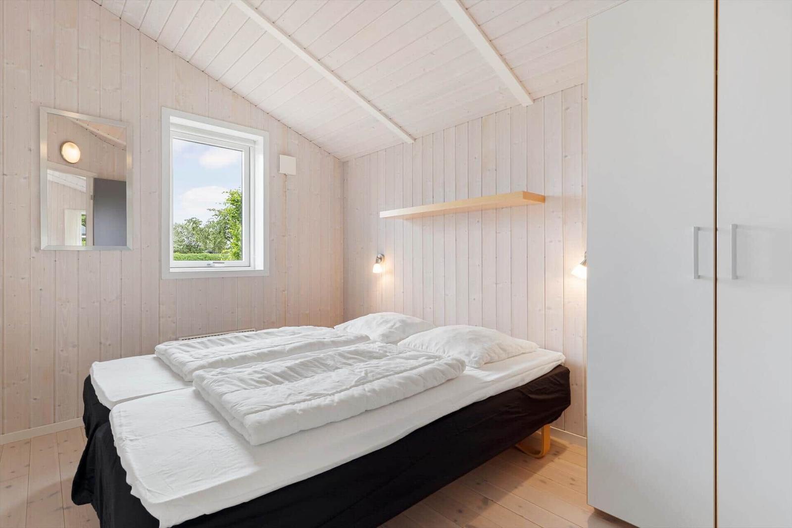 Schlafzimmer mit Doppelbett, Fenster und Kleiderschrank.